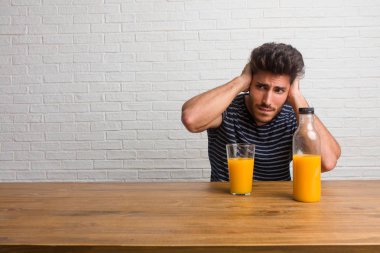 Eller, kızgın ve bazı ses işitme yorgun kulaklarıyla kapsayan bir masada oturan genç yakışıklı ve doğal adam. Bir kahvaltı yapıyor, portakal suyu ve tahıl bowl içerir.