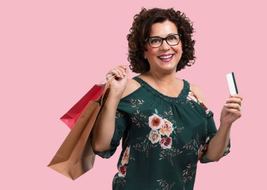 Orta yaşlı kadın neşeli ve gülümseyen, yeni banka kartı ve alışveriş torbaları tutan çok heyecanlı, alışverişe gitmek için hazır