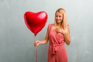 Birine aşık romantik bir jest ya da bir arkadaş için bir sevgi gösterisi zarif sarışın genç kadın portresi. Bir kırmızı kalp balon holding.