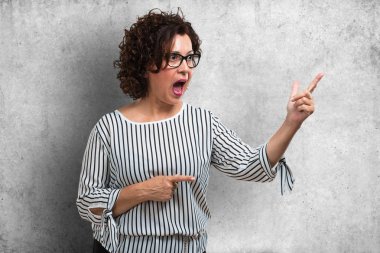 Sürpriz bir şey, doğal ve rahat sunan gülümseyen tarafına işaret orta yaşlı kadın