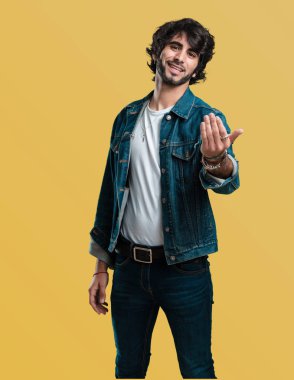 Pozitif ve güler yüzlü genç yakışıklı adam gel, kendinden emin ve gülümseyen bir hareketi el ile yapmak için davet