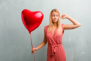 Eller, kızgın ve bazı ses işitme yorgun kulaklarıyla kapsayan zarif sarışın genç kadın portresi. Bir kırmızı kalp balon holding.