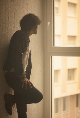 Genç yakışıklı adam neşeli ve kendine güvenen ayakta pencere kapalı karşı 