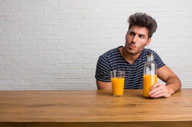 Bir tablo şüphe ve karışık, düşünme, bir fikir ya da bir şey hakkında endişe üzerine oturan genç yakışıklı ve doğal adam. Bir kahvaltı yapıyor, portakal suyu ve tahıl bowl içerir.