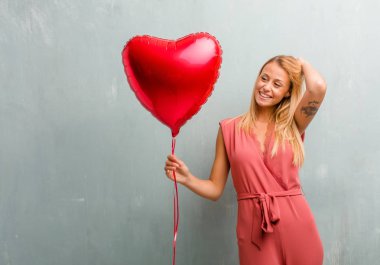 zarif genç sarışın kadın kırmızı kalp balon tutan mutlu.