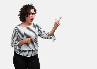 Sürpriz bir şey, doğal ve rahat sunan gülümseyen tarafına işaret orta yaşlı kadın