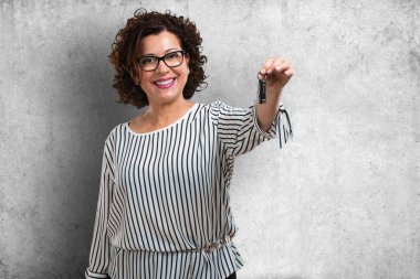 Arabanın anahtarları kendine güvenen, yeni bir araba başlatmak için onları sunan tutan kadın mutlu ve gülümseyerek, orta yaşlı