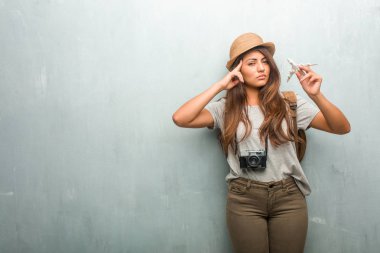 Genç gezgin latin kadın konsantrasyonu jest yapma bir duvar adama karşı portresi, seyir dümdüz bir hedef odaklı. Bir uçak model holding.