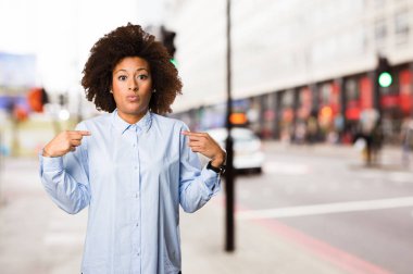 Genç siyah kadın kendini bulanık arka plan üzerine işaret