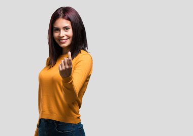 Genç ve güzel bir kadın, kendinden emin ve gülümsüyor. Elleriyle jest yapıyor. Olumlu ve arkadaş canlısı.