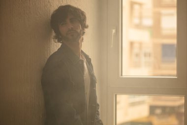 Genç yakışıklı adam neşeli ve kendine güvenen ayakta pencere kapalı karşı 