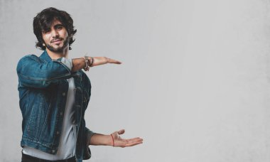 Elleriyle bir şey tutan, bir ürün, gülümseyen ve neşeli gösterilen, hayali bir nesne sunan yakışıklı delikanlı