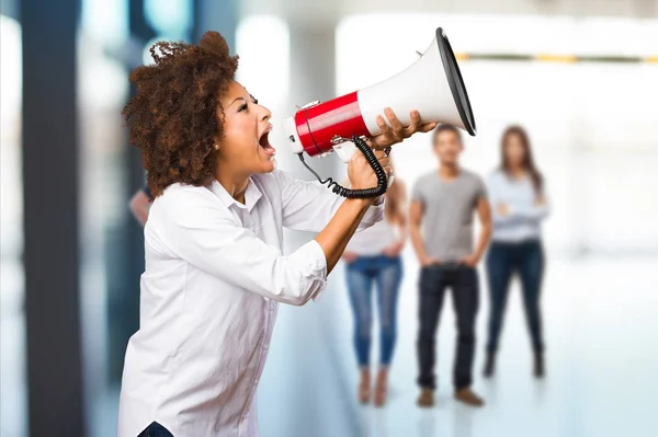 young black woman shouting on the megaphone with blurred people in background