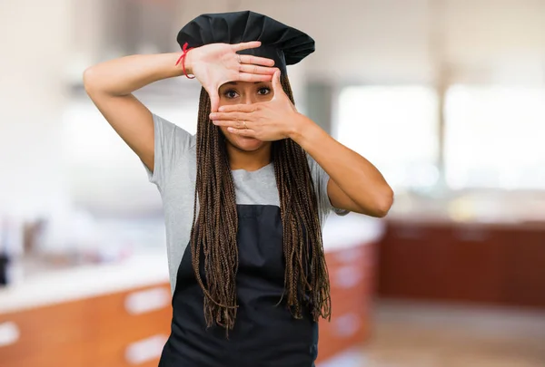 Portrait of a young black baker woman feels worried and scared, looking and covering face, concept of fear and anxiety