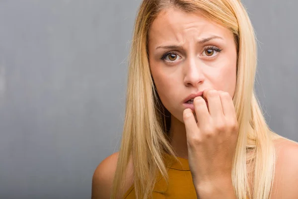 portrait of natural young blonde woman biting nails