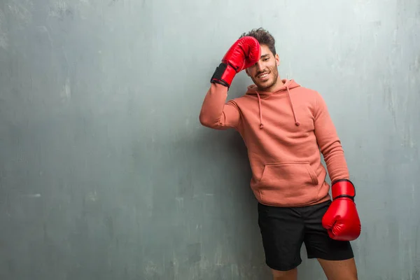 年轻健身男子与拳击手套对垃圾墙笑和有乐趣 — 图库照片