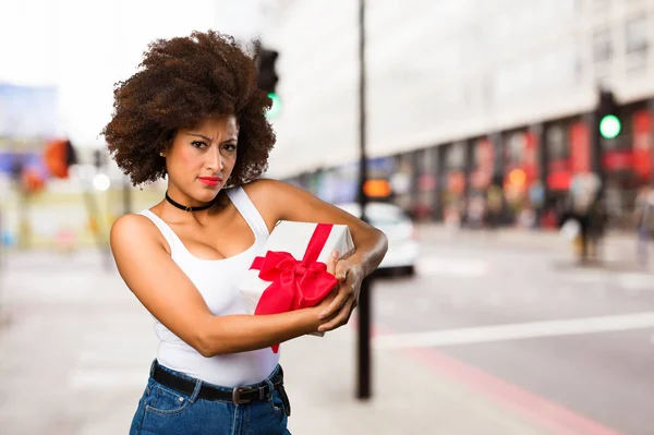 young black woman holding a gift on blurred background