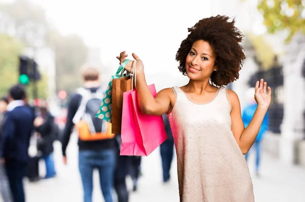 背景をぼかした写真に買い物袋を保持している若い黒人女性 — ストック写真