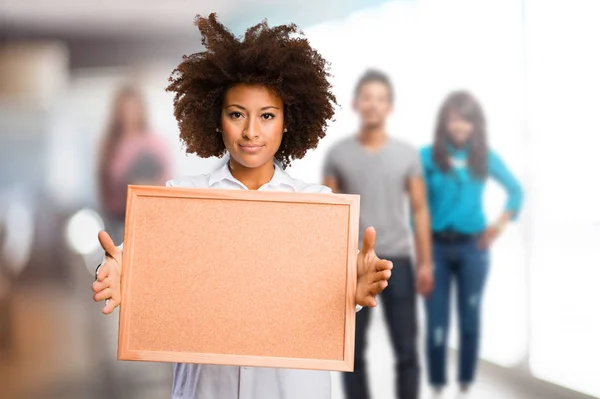 在背景模糊的人持有软木板的年轻的黑色妇女 — 图库照片