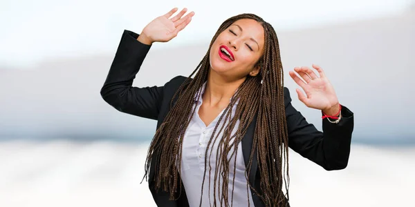 Portrait of a young black business woman Listening to music, dancing and having fun, moving, shouting and expressing happiness, freedom concept