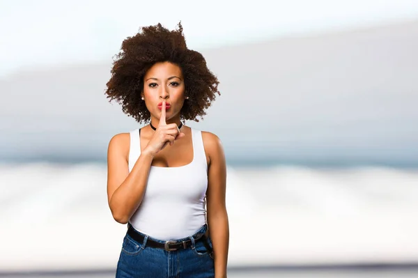 young black woman doing silence gesture on blurred background