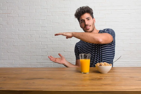 Joven Hombre Guapo Natural Sentado Una Mesa Sosteniendo Algo Con — Foto de Stock