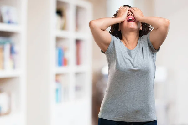 Middle aged woman frustrated and desperate, angry and sad with hands on head