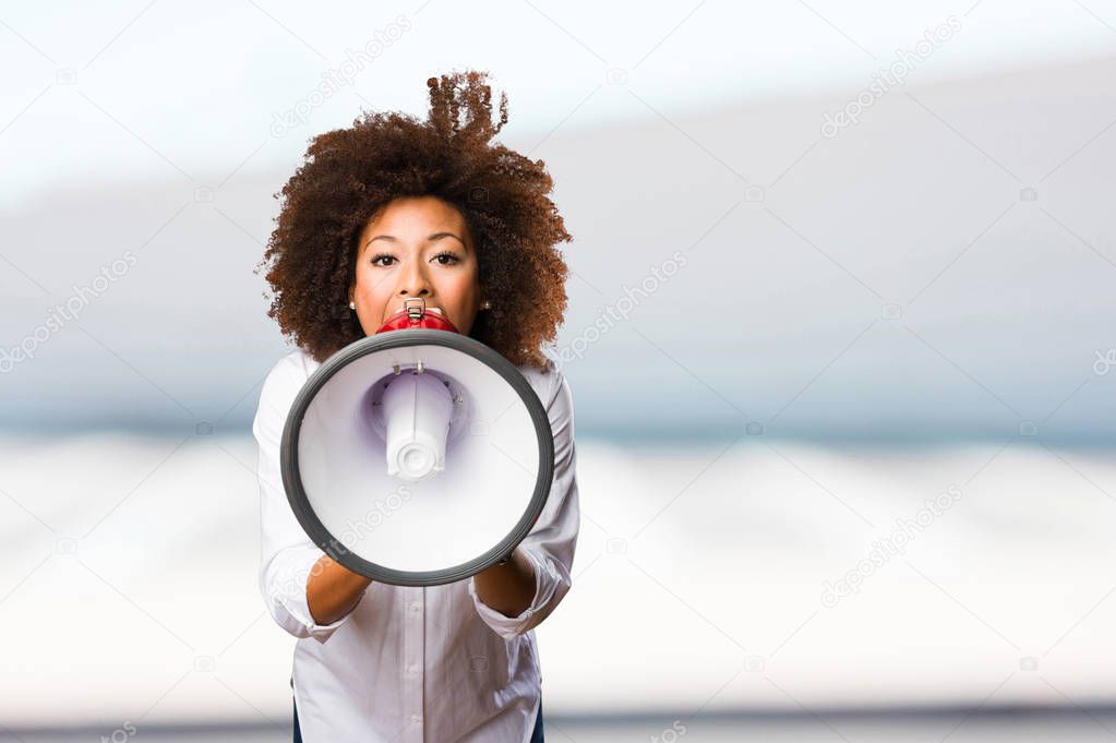 young black woman shouting on the megaphone on blurred background