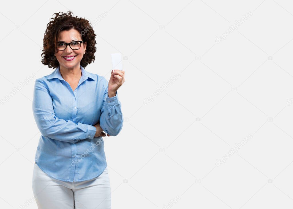 Middle aged woman smiling confident, offering a business card, has a thriving business, copy space to write whatever you want