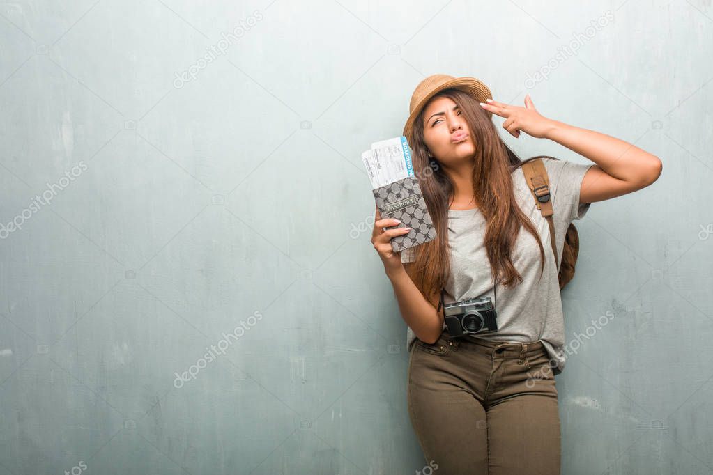 Portrait of young traveler latin woman against wall making suicide gesture