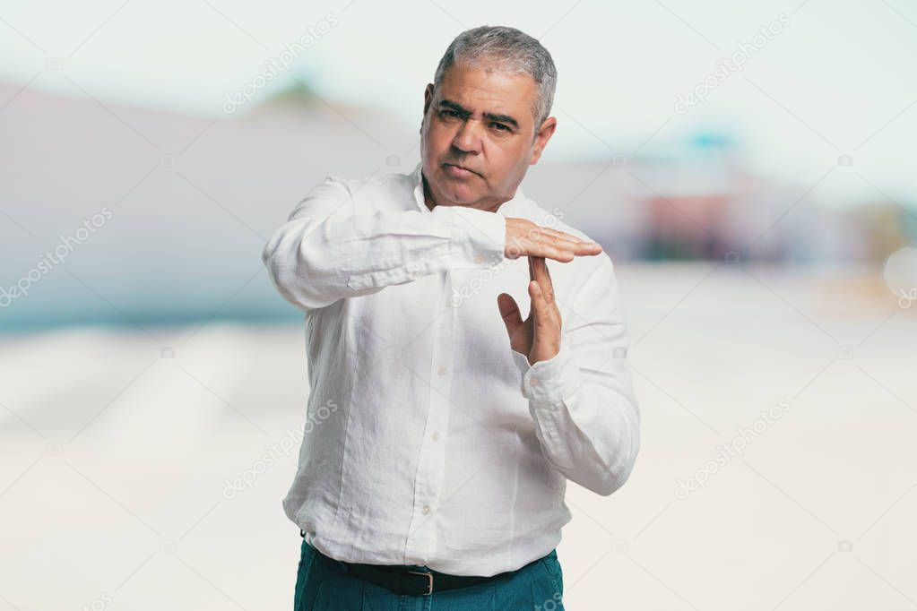 Middle aged man tired and bored, making a timeout gesture, needs to stop because of work stress, time concept