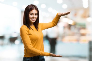 Elleriyle bir şey tutan, bir ürün, gülümseyen ve neşeli gösterilen, hayali bir nesne bir kafeterya olarak sunan kadın genç güzel