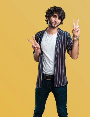 Genç yakışıklı adam eğlenceli ve mutlu, pozitif ve doğal, zafer, barış kavramı bir jest yapar