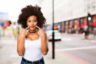 Genç siyah kadın ağzını bulanık arka plan üzerine işaret