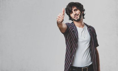Genç yakışıklı adam neşeli ve heyecanlı, gülümseyerek onu başparmak, başarı ve onay, kavram yükselterek ok ve jest