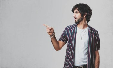 Sürpriz bir şey, doğal ve rahat sunan gülümseyen genç yakışıklı adam tarafına işaret