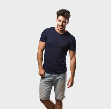 Genç yakışıklı adam ayakta gülen ve having fun, rahat ve neşeli olmak hissediyor kendinden emin ve başarılı