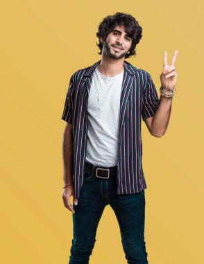 Genç yakışıklı adam eğlenceli ve mutlu, pozitif ve doğal, zafer, barış kavramı bir jest yapar