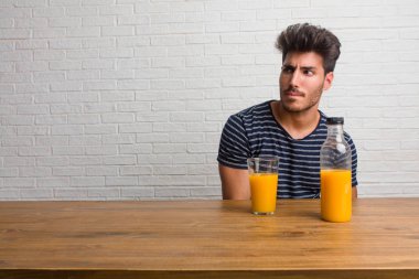 Bir tablo şüphe ve karışık, düşünme, bir fikir ya da bir şey hakkında endişe üzerine oturan genç yakışıklı ve doğal adam. Bir kahvaltı yapıyor, portakal suyu ve tahıl bowl içerir.