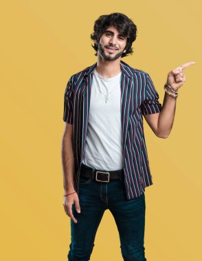 Sürpriz bir şey, doğal ve rahat sunan gülümseyen genç yakışıklı adam tarafına işaret