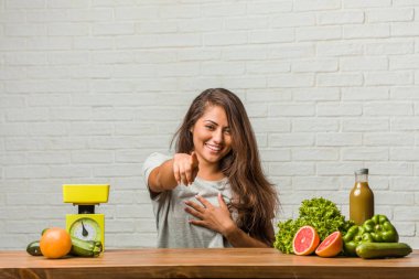 Diyet kavramı. Portre sağlıklı genç bir latin kadın neşeli ve gülümseyerek önüne işaret