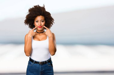 Genç siyah kadın ağzını bulanık arka plan üzerine işaret