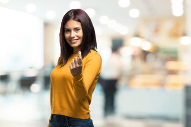 Gel, kendinden emin ve gülümseyen bir hareketi el ile yapmak için davet kadın pozitif ve güler yüzlü bir kafeteryada genç güzel