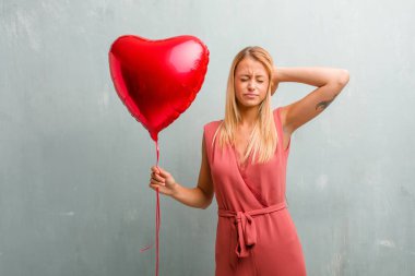 Eller, kızgın ve bazı ses işitme yorgun kulaklarıyla kapsayan zarif sarışın genç kadın portresi. Bir kırmızı kalp balon holding.