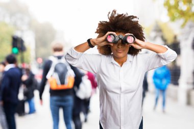 Genç siyah kadın arka plan bulanık üzerinde dürbün üzerinden seyir