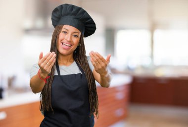 Portre pozitif ve güler yüzlü bir genç siyah baker kadının gel, kendinden emin ve gülümseyen bir hareketi el ile yapmak için davet