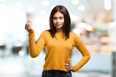 Genç güzel kadın bir tipik İtalyan jest, gülümseyen ve dümdüz bakarak, sembol veya el, bir kafeteryada çok doğal bir ifadeyle yapıyor