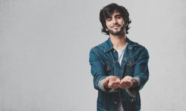 Elleriyle bir şey tutan, bir ürün, gülümseyen ve neşeli gösterilen, hayali bir nesne sunan yakışıklı delikanlı