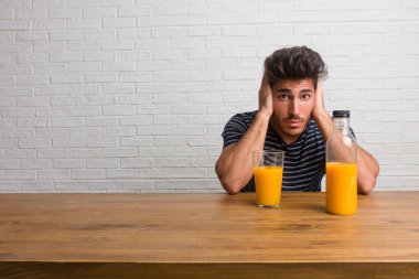 Eller, kızgın ve bazı ses işitme yorgun kulaklarıyla kapsayan bir masada oturan genç yakışıklı ve doğal adam. Bir kahvaltı yapıyor, portakal suyu ve tahıl bowl içerir.