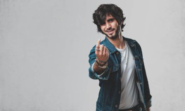 Pozitif ve güler yüzlü genç yakışıklı adam gel, kendinden emin ve gülümseyen bir hareketi el ile yapmak için davet